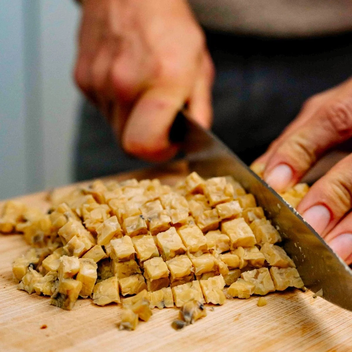 Luca schneidet den bissfesten Bio Tempeh in Würfel für die Zubereitung.
