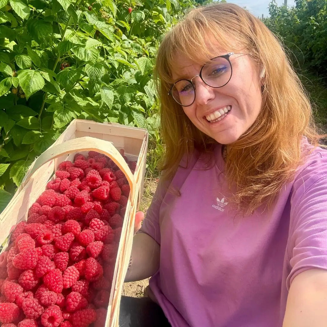 Gründerin Jana auf dem Feld mit frisch gepflückten Himbeeren.