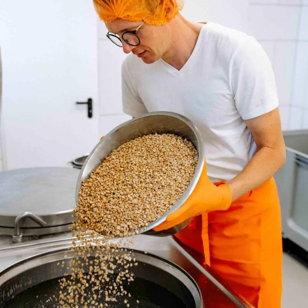 Luca füllt Bio-Kichererbsen für die Kichererbse-Tempeh Produktion in den Kessel.