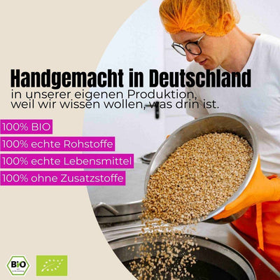 Mitarbeiter in Hygienekleidung gießt Bio-Sojabohnen in Industriekessel zur Tempeh-Herstellung in nachhaltiger Manufaktur common